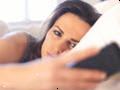 Ulykkelig kvinde i sengen kigger på hendes mobiltelefon Ulykkelig kvinde i sengen kigger på hendes mobiltelefon